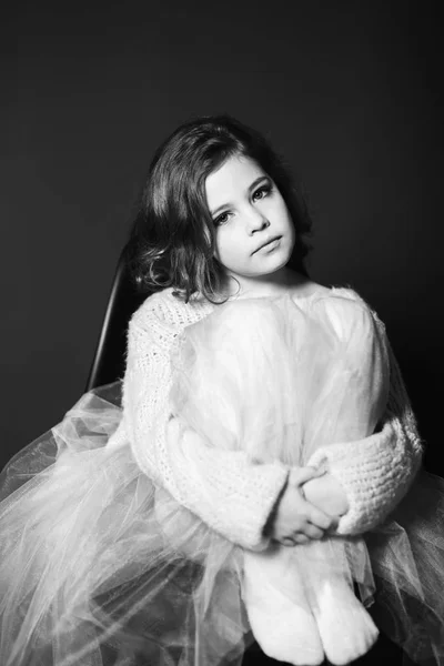Kleines schönes Mädchen mit braunen Haaren im hellen Pullover und mit einem Rock aus Tüll. eine Prinzessin posiert für einen Fotografen. — Stockfoto