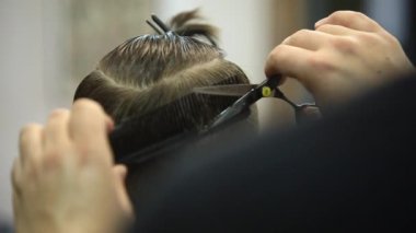 Çocuğun saçlarını Kuaför içinde bir sandalyede oturur.