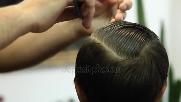 Niño en un corte de pelo en el barbero se sienta en una silla . — Vídeos de Stock