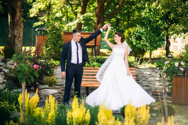 Ungt par, bruden och brudgummen promenader och njuta av sin bröllopsdag. Sunshine. Sommar. — Stockfoto