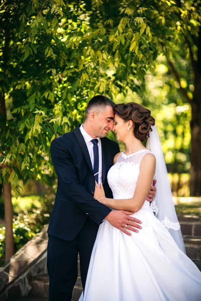 Fiatal pár, a menyasszony és a vőlegény, séta, és élvezi az esküvő napján. Napsütés. Nyári. — Stock Fotó