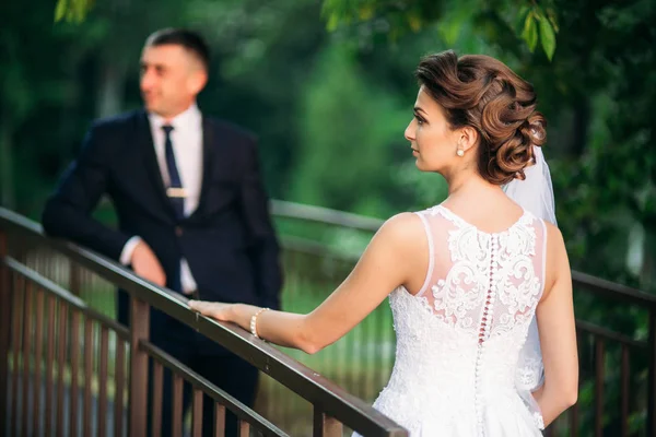 Bella coppia a piedi nel parco nel giorno del loro matrimonio. Tempo soleggiato . — Foto Stock