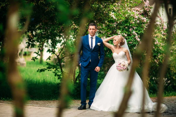 Os recém-casados estão andando no parque no dia do casamento. A noiva e o noivo Desfrutando no dia do casamento. Tempo ensolarado. Primavera . — Fotografia de Stock