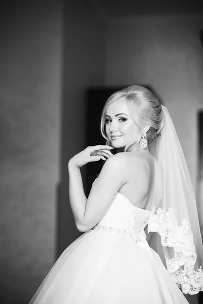 Retrato de una novia en un vestido de novia. La novia se viste en el hotel . — Foto de Stock