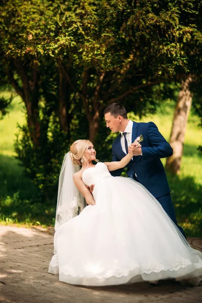 Os recém-casados estão andando no parque no dia do casamento. A noiva e o noivo Desfrutando no dia do casamento. Tempo ensolarado. Primavera . — Fotografia de Stock