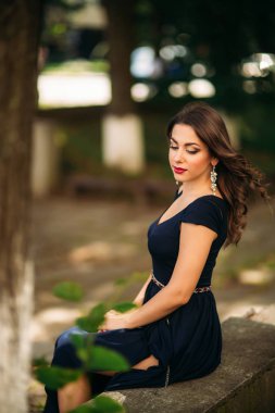 Mavi elbiseli güzel bir kız parkta yürüyor.