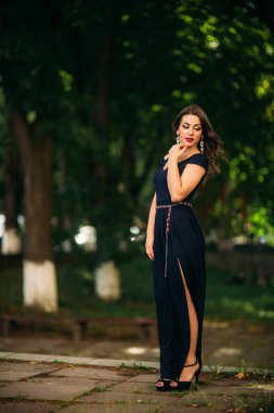 Mavi elbiseli güzel bir kız parkta yürüyor.