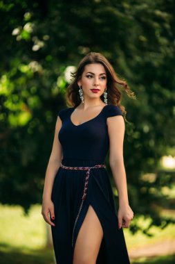 Mavi elbiseli güzel bir kız parkta yürüyor.