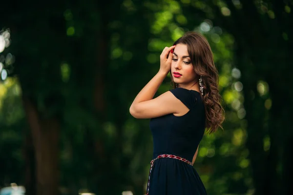 Ein schönes Mädchen in einem blauen Kleid spaziert durch den Park. — Stockfoto