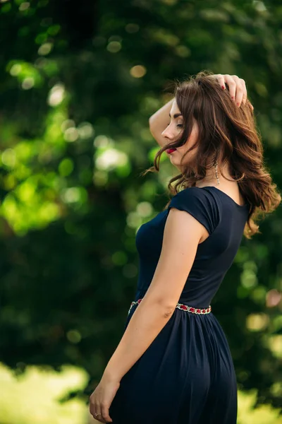 Una bella ragazza con un vestito blu cammina nel parco . — Foto Stock