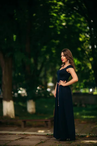 Une belle fille en robe bleue se promène dans le parc . — Photo
