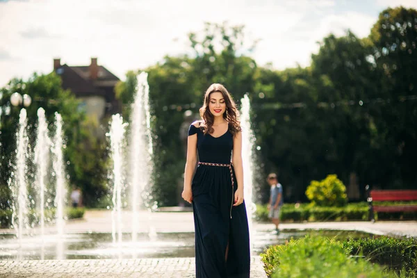 Een meisje loopt rond de stad, in de buurt van een grote fontein. — Stockfoto