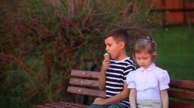 Erkek ve kız bankta oturuyor. Park ve darbe dandelions çalıştırmak