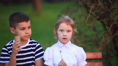 Erkek ve kız bankta oturuyor. Park ve darbe dandelions çalıştırmak