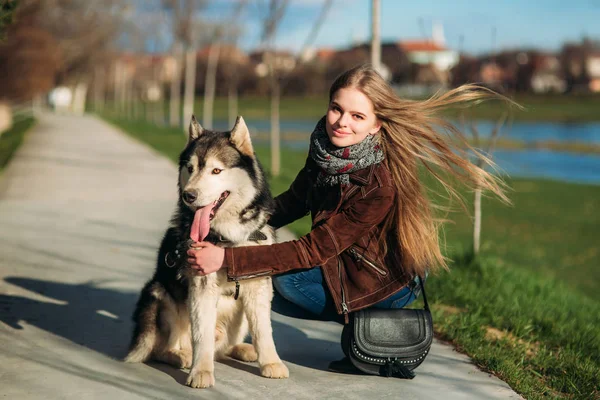 Ein Mädchen geht mit einem Hund die Böschung entlang. schöner Husky-Hund. der Fluss. Frühling. — Stockfoto