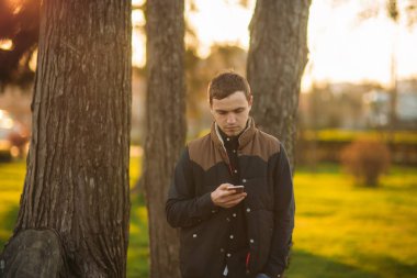 Koyu mavi gömlekli bir parkta genç bir adam. Bahar.