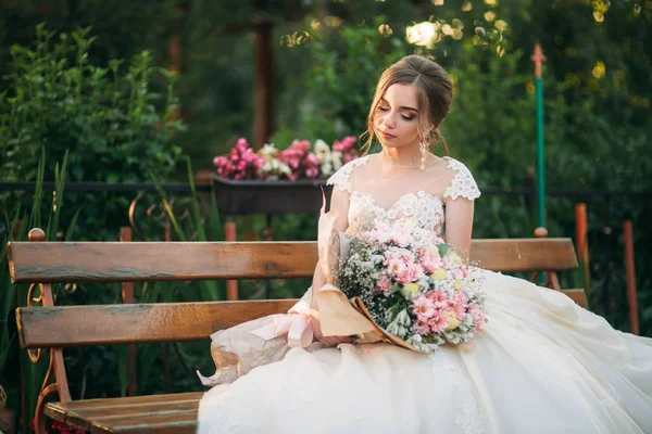 Young girl in wedding dress in park posing for photographer. — Stock Photo, Image