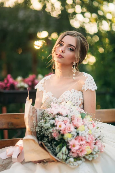 Junges Mädchen im Hochzeitskleid posiert im Park für Fotograf. — Stockfoto