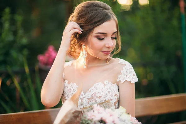 Junges Mädchen im Hochzeitskleid im Park posiert für Fotografen. Porträt — Stockfoto