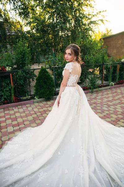 Young girl in wedding dress in park posing for photographer. — Stock Photo, Image