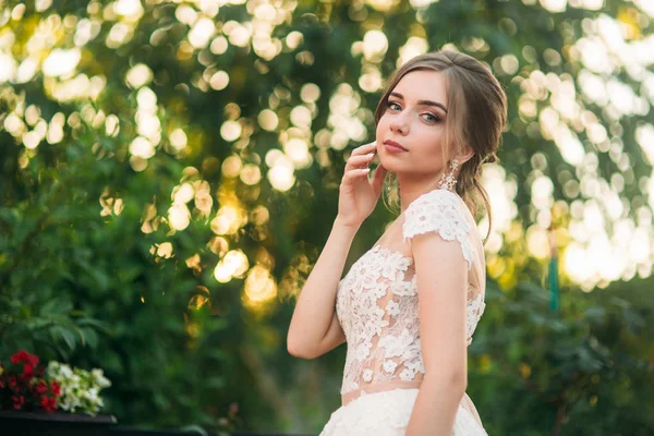 Молодая девушка в свадебном платье в парке позирует для фотографа. портрет — стоковое фото
