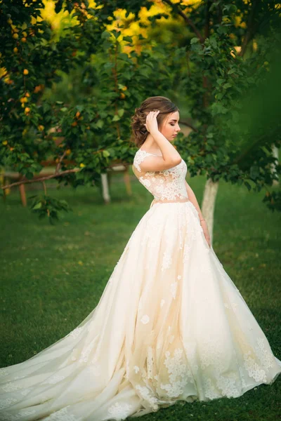 Young girl in wedding dress in park posing for photographer. — Stock Photo, Image