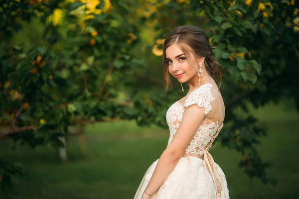 Junges Mädchen im Hochzeitskleid posiert im Park für Fotograf. — Stockfoto