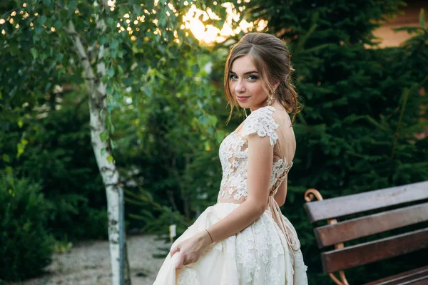 Young girl in wedding dress in park posing for photographer. — Stock Photo, Image