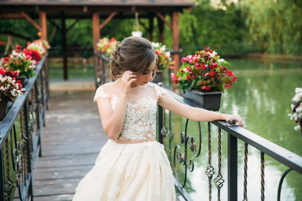 Jovem em vestido de noiva no parque posando para fotógrafo. lago — Fotografia de Stock