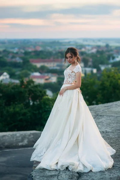 Молодая девушка в свадебном платье на фоне города на закате . — стоковое фото