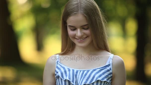 Bella ragazza disegna un disegno nel parco utilizzando una tavolozza con vernici e una spatola. Cavalletto e tela con un'immagine . — Video Stock