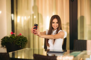 İş kadını çalışmak için bir tablet ve telefon kullanır. Kafede kız gülümsüyor