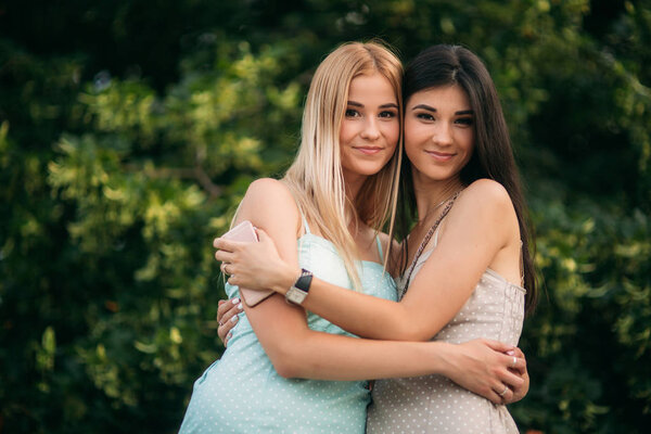 Brunette and blonde are photographed and enjoy life. Sunny day. Summer.