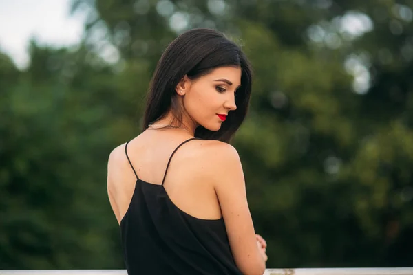 Schöne Mädchen, die für den Fotografen posieren. zwei Schwestern in schwarz-rotem Kleid. Lächeln, sonniger Tag, Sommer. — Stockfoto