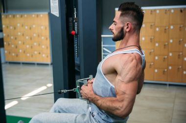 Genç bir atlet spor salonunda eğitiyor. Sırt ve göğüs kaslarının gösterir