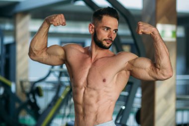 Genç atlet ile bir gövde bir tuğla duvar arka plan fotoğraf için poz. Vücut geliştirmeci, atlet pompalanır kaslar ile.