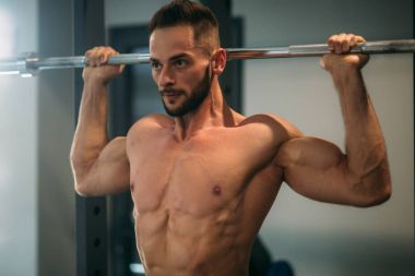 Genç bir atlet spor salonunda eğitiyor. Sırt ve göğüs kaslarının gösterir