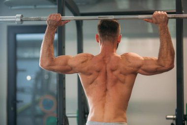 Genç bir atlet spor salonunda eğitiyor. Sırt ve göğüs kaslarının gösterir