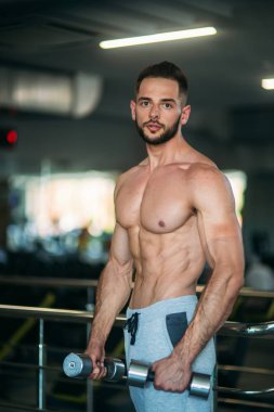 Genç bir atlet spor salonunda eğitiyor. Sırt ve göğüs kaslarının gösterir