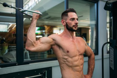 Genç bir atlet spor salonunda eğitiyor. Sırt ve göğüs kaslarının gösterir