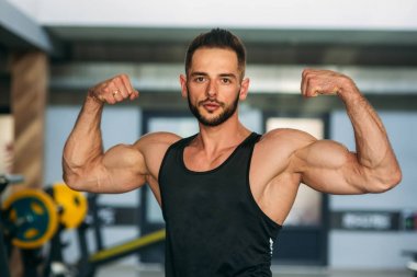 Genç atlet ile bir gövde bir tuğla duvar arka plan fotoğraf için poz. Vücut geliştirmeci, atlet pompalanır kaslar ile.