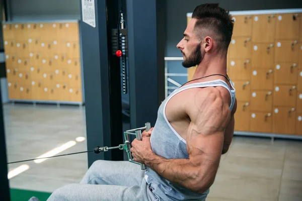 Genç bir atlet spor salonunda eğitiyor. Sırt ve göğüs kaslarının gösterir