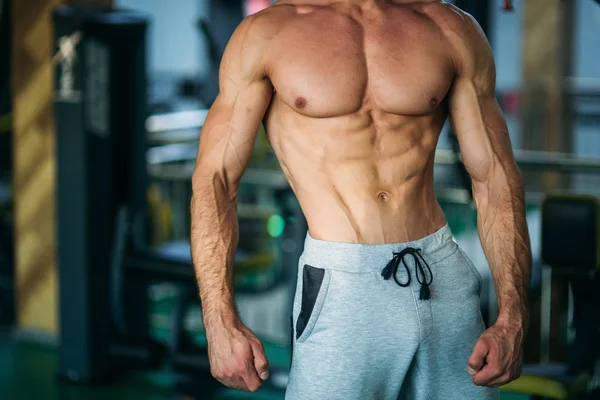 Giovane atleta in posa con un busto per la fotografia su uno sfondo muro di mattoni. Culturista, atleta con muscoli pompati . — Foto Stock