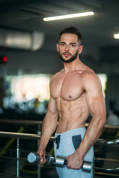 Um jovem atleta treina no ginásio. Mostra os músculos das costas e do peito — Fotografia de Stock