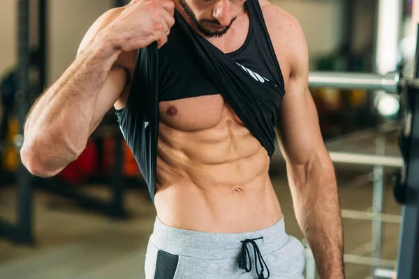 Genç atlet ile bir gövde bir tuğla duvar arka plan fotoğraf için poz. Vücut geliştirmeci, atlet pompalanır kaslar ile.