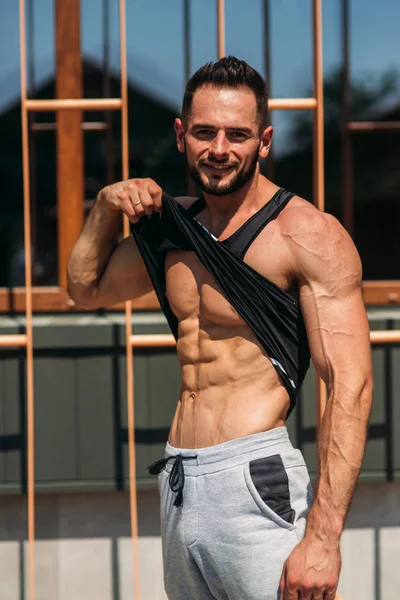 Genç atlet ile bir gövde bir tuğla duvar arka plan fotoğraf için poz. Vücut geliştirmeci, atlet pompalanır kaslar ile.