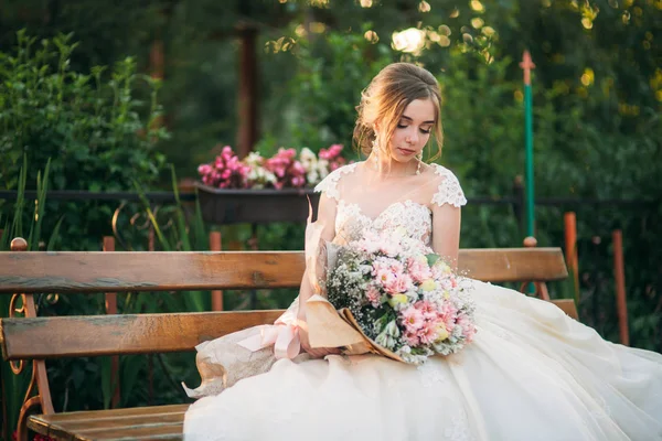 Young girl in wedding dress in park posing for photographer. Sunny weather, summer. — Stock Photo, Image