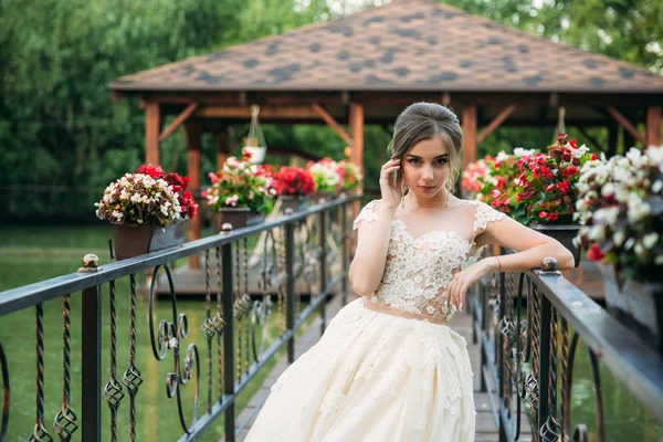 Jovem em vestido de noiva no parque posando para fotógrafo. Tempo ensolarado, verão . — Fotografia de Stock