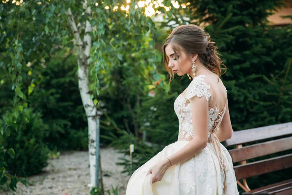 Jovem em vestido de noiva no parque posando para fotógrafo. Tempo ensolarado, verão . — Fotografia de Stock