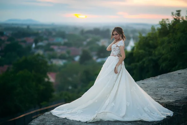 Chica joven en vestido de novia en el fondo de la ciudad al atardecer. Verano — Foto de Stock